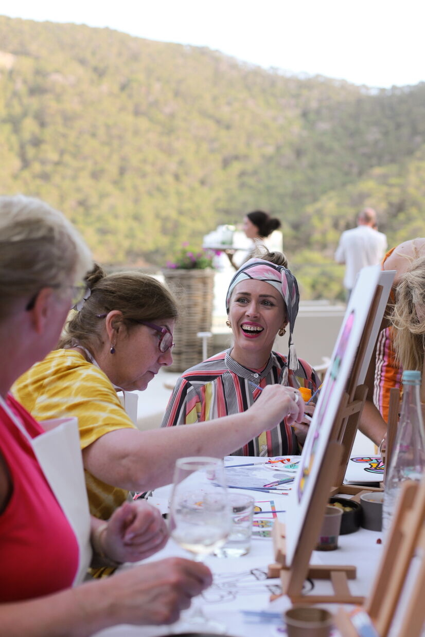 3 people painting and smiling while sitting outside