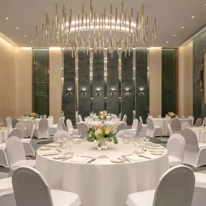 image of empty ballroom with multiple rounds tables, chairs and white table cloths