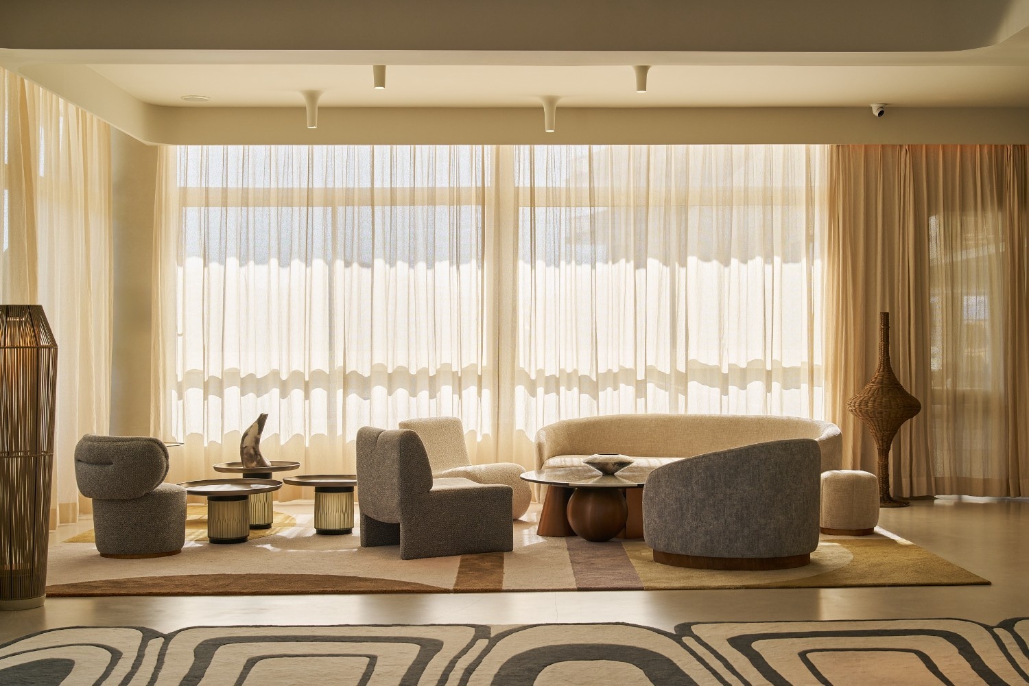 seating area with a couple of low seats next to a window that is covered by light curtains
