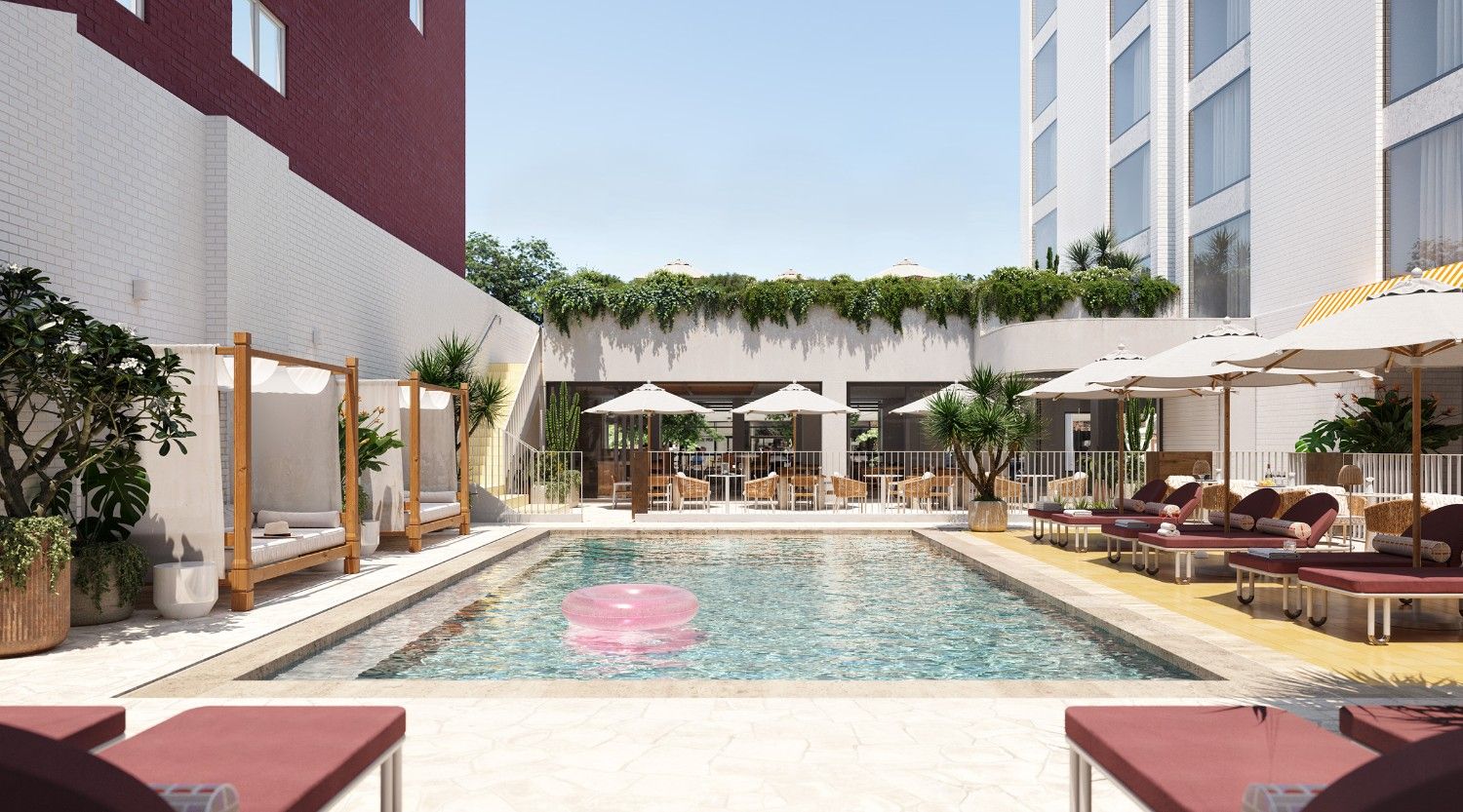 Bright outdoor courtyard pool with loungers and umbrellas, and cabana daybeds.