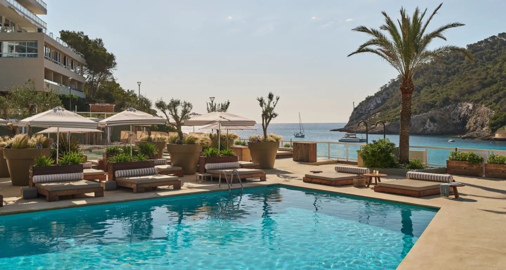 image of pool with empty sunbed chairs next to it